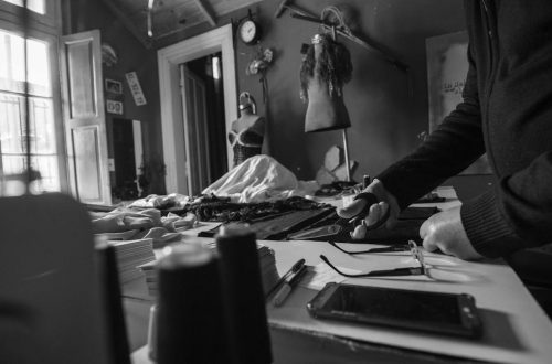 A black and white image capturing a seamstress working in a vintage workshop with tools.