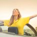 A cheerful woman in a yellow shirt enjoys freedom on a sunny drive in a convertible.